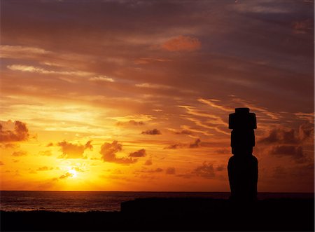 Silhouetted at sunset on Ahu Kote Riku,a single well preserved moai sits on top of one of the three ahus or platforms of the ceremonial centre of Tahai. Tahai is just a short walk from Hanga Roa,the island's main settlement. Stock Photo - Rights-Managed, Code: 862-03352114