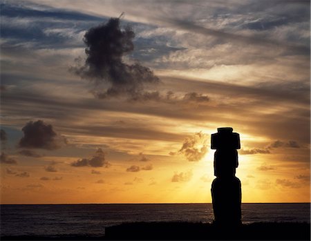 Silhouette au coucher du soleil sur Ahu Kote Riku, un moai bien préservé unique repose sur le dessus de l'un de le trois ahus ou plateformes du centre cérémoniel de Tahai. Tahai est juste à quelques pas de Hanga Roa, principale agglomération de l'île. Photographie de stock - Rights-Managed, Code: 862-03352115