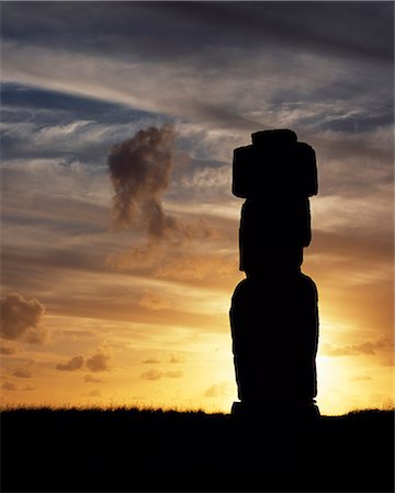 Silhouetted at sunset on Ahu Kote Riku,a single well preserved moai sits on top of one of the three ahus or platforms of the ceremonial centre of Tahai. Tahai is just a short walk from Hanga Roa,the island's main settlement. Stock Photo - Rights-Managed, Code: 862-03352117