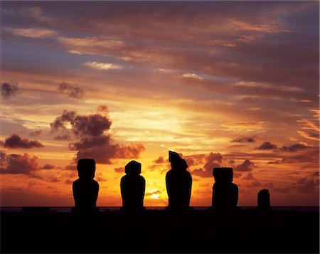 Silhouette au coucher du soleil sur Ahu Vai Uri, quatre tanné moais et du tronc de faire d'un cinquième s'asseoir sur le dessus de le trois ahus ou plates-formes de centre cérémoniel de Tahai. Tahai est juste à quelques pas de Hanga Roa, principale agglomération de l'île. Photographie de stock - Rights-Managed, Code: 862-03352119