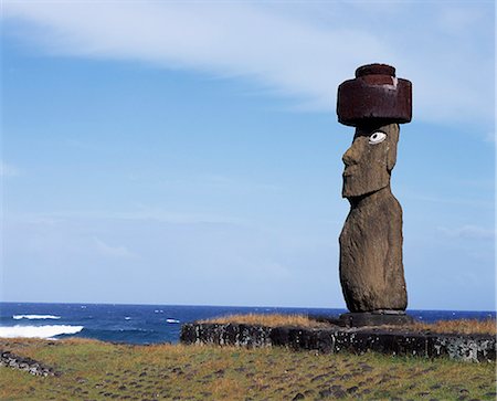 At Ahu Kote Riku,a single well preserved moai with white eyes and a red topknot sits on top of one of the three ahus or platforms of the ceremonial centre of Tahai. Tahai is just a short walk from Hanga Roa,the island's main settlement. Stock Photo - Rights-Managed, Code: 862-03352113