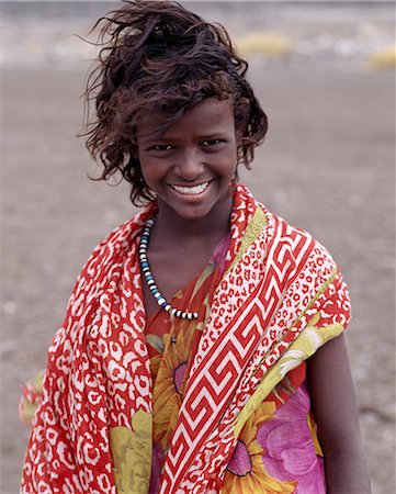 djibouti africa - A pretty tousle-haired girl of the nomadic Afar tribe wears bright colours in stark contrast to the drab,windswept surroundings of Lake Abbe. Stock Photo - Rights-Managed, Code: 862-03352642