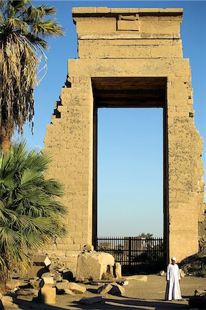 simsearch:862-03352797,k - Un homme égyptien en tenue traditionnelle se tient devant une passerelle colossale dans le Temple de Karnak, Luxor. Photographie de stock - Rights-Managed, Code: 862-03352749