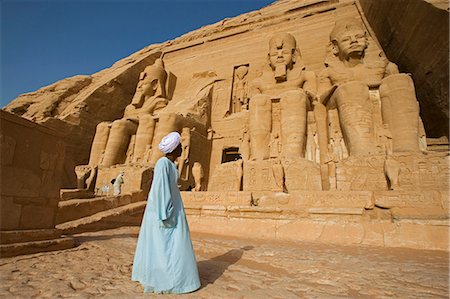 A temple guardian stands in front of the facade of Abu Simbel. The entire site was moved 200m in the 1960s in order to save it from the rising waters of Lake Nasser,Egypt Fotografie stock - Rights-Managed, Codice: 862-03352805