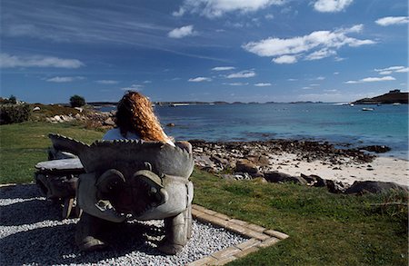 Looking out across Old Grimsby towards Blockhouse Point from the Island Hotel,Tresco. Wooden seats are carved to the shape of crabs. Stock Photo - Rights-Managed, Code: 862-03353027