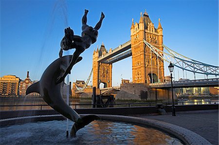 Tower Bridge at dawn. Construction of the bridge started in 1886 and took 8 years. The central span can be raised to allow ships to travel upriver. The bridge is close to the Tower of London,which gives it its name. It is often mistaken for London Bridge,the next bridge upstream. Stock Photo - Rights-Managed, Code: 862-03353094