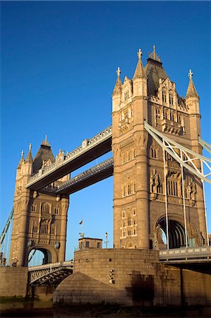 Tower Bridge at dawn. Construction of the bridge started in 1886 and took 8 years. The central span can be raised to allow ships to travel upriver. The bridge is close to the Tower of London,which gives it its name. It is often mistaken for London Bridge,the next bridge upstream. Fotografie stock - Rights-Managed, Codice: 862-03353095