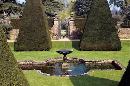 England,Dorset. Athelhampton House is one of the finest examples of 15th century domestic architecture in the country. Medieval in style predominantly and surrounded by walls,water features and secluded courts. Here the topiary of the Great Court is a masterpiece of Francis Inigo Thomas. Stock Photo - Rights-Managed, Code: 862-03353621