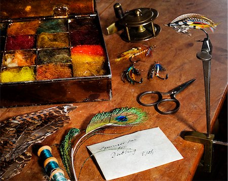 pesca con la mosca - UK. Antique fly-tying equipment with a traditionally tied salmon fly in the vice on a fly-tiers bench Fotografie stock - Rights-Managed, Codice: 862-03353766