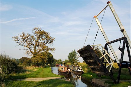 England,Shropshire,Whitchurch. A barge passes under a cantiliver bridge on a tranquil section of the Shropshire Union Canal. Stock Photo - Rights-Managed, Code: 862-03353767