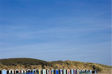 England,Devon. On the north Devon coast at Saunton Sands near Barnstable,a line of mulitcoloured beach huts sits in front a protective sand dune. Stock Photo - Rights-Managed, Code: 862-03353860