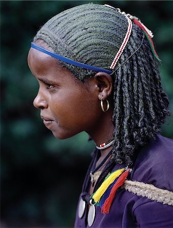 ethiopian people - Une jeune fille éthiopienne avec les cheveux tressé inhabituelle ; le sommet de sa tête a été enduit d'une substance verdâtre. Ses deux pendentifs sont fabriqués à partir de thalers Maria Theresa anciennes pièces d'argent frappées en Autriche, qui ont été largement utilisés comme monnaie dans le nord de l'Éthiopie et Arabie jusqu'à la fin de la seconde guerre mondiale. Photographie de stock - Rights-Managed, Code: 862-03353964