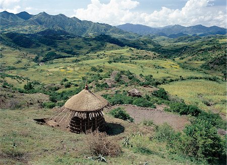 simsearch:400-05371971,k - Scenery between Desse and Bati in the Welo Province of northern Ethiopia with an unfinished thatched house in the foreground. Upturned clay pots are often placed over the protruding centre poles of houses to prevent rain getting in. . Foto de stock - Con derechos protegidos, Código: 862-03353963