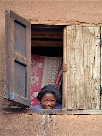 A girl peeps out of the upstairs window of her home near Ambositra,Madagascar Stock Photo - Rights-Managed, Code: 862-03364009