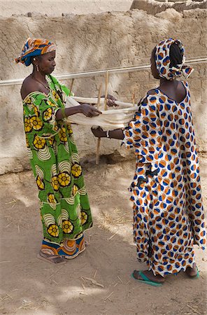 fil (textile) - Mali, Senossa. Deux femmes Peul préparent des écheveaux de fils de coton de la grande longueur, qu'ils ont tourné autour des murs de leur maison. Le Mali est le deuxième plus grand producteur de coton de l'Afrique. Photographie de stock - Rights-Managed, Code: 862-03364149