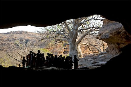 dogon - Mali, pays Dogon. Des enfants se rassemblent à l'entrée du tunnel de Bongo, qui est une formation rocheuse naturelle près de Sangha, un joli village Dogon construit parmi les rochers au sommet de l'escarpement de Bandiagara. Photographie de stock - Rights-Managed, Code: 862-03364188