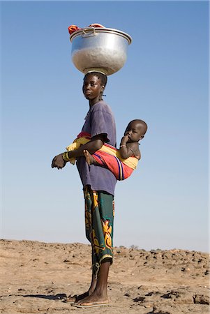 escarpement - Au Mali, pays Dogon, Sangha. Une femme rentre chez lui de lessive dans une rivière proche de son enfant en bandoulière sur son dos et un grand bol de métal sur la tête. Photographie de stock - Rights-Managed, Code: 862-03364181
