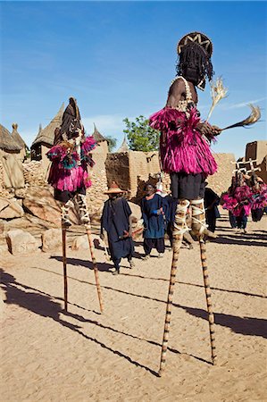 simsearch:862-03364178,k - Mali,Dogon Country,Tereli. Masked stilt dancers wearing coconut shells as breasts perform at the Dogon village of Tereli. Tereli is situated among rocks at the base of the spectacular 120-mile-long Bandiagara escarpment. The mask dance is staged at funeral ceremonies to appease the dead and speed them on their way to the ancestral world. Stock Photo - Rights-Managed, Code: 862-03364205