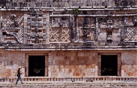 Mexico,Yucatan,Uxmal. A female tourist walks through 'The Nunnery' quadrangle at the Mayan site of Uxmal. This is one of the best preserved Mayan sites displaying the 'Puuc' style of architecture,named after the Puuc Hills nearby. Foto de stock - Con derechos protegidos, Código: 862-03364385