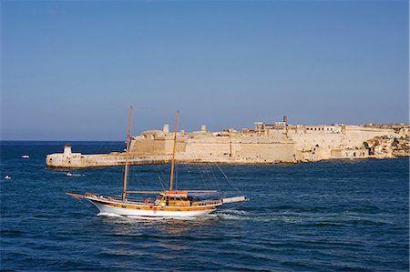 simsearch:862-03354213,k - Malta,Valletta. A fishing boat motors out of the entrance to the Grand Harbour past Ricasoli Point. Foto de stock - Direito Controlado, Número: 862-03364491