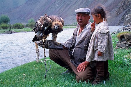 falconry - Mongolia,Khovd (also spelt Hovd) aimag (region),Kasakh hunter with eagle by the Khovd River,with a small child. Eagles are trained by the Kasakh people of Western Mongolia and used in hunting foxes and smaller steppe creatures for the pot. Stock Photo - Rights-Managed, Code: 862-03364515