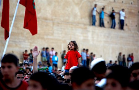 fez - Morocco,Fes. Against the backdrop of the ancient walls of Fes,a girl stands out in the crowd at a free concert in the Place Boujloud during the Fes Festival of World Sacred Music. Foto de stock - Con derechos protegidos, Código: 862-03364808