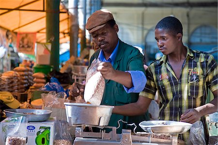 simsearch:862-03437266,k - Mozambique,Maputo. A stall holder weighs his produce with the help of his assistant in the Central Market in downtown Maputo. The Central Market,commonly known as Mercardo Central,is on Avenida 25 de Abril in downtown Maputo. The market is a good place to buy a variety of fresh and frozen fish aswell as vegetables,fruit,carvings,and baskets. Stock Photo - Rights-Managed, Code: 862-03365013