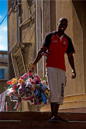 Mozambique,Maputo. A street vendor carries his products around the Polana district of Maputo - including toys,sweets and hair styling products. Maputo is the capital of Mozambique. It is a bustling,attractive port city with a population of at least 1.5 million. Maputo is a very agreeable city which is considerably safe and more attractive when compared to other African capitals. Stock Photo - Rights-Managed, Code: 862-03365025