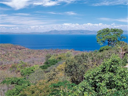 simsearch:862-03365042,k - Malawi, lac Malawi, collier. Une belle vue du lac Malawi, prise depuis la route menant vers le bas de l'escarpement de la vallée du Rift au collier. Les collines lointaines sont en Mozambique.Lake au Malawi est la quintessence d'un lac de la vallée du Rift - longue, étroite et peu profonde. 363 km de long et qui couvre un cinquième du Malawi, il a une faune de poissons plus diversifiée que tous les autres lacs du monde. Photographie de stock - Rights-Managed, Code: 862-03365068