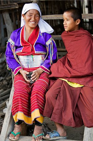 Myanmar. Burma. Wanpauk village. A proud Palaung woman sits beside her son - a novice monk. She displays her wealth by wearing broad silver belts around her waist. Foto de stock - Con derechos protegidos, Código: 862-03365202