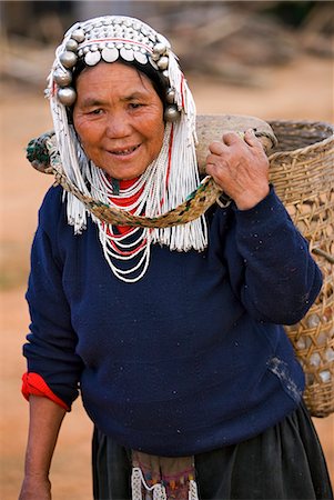 Myanmar,Burma,Namu-op. An Akha woman wearing a headdress of silver and glass beads,carries a large bamboo basket supported at the back of her neck by a yoke. Stock Photo - Rights-Managed, Code: 862-03365229