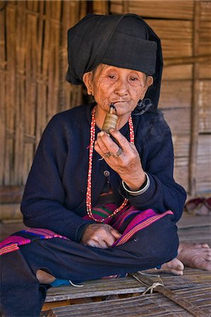 Myanmar, Birmanie, Wan doi. Une vieille femme de la tribu Ann en habit traditionnel assis sur l'estrade de sa maison qu'elle fume la pipe. Photographie de stock - Rights-Managed, Code: 862-03365254