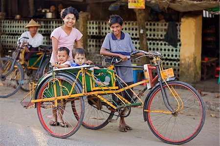 simsearch:862-03365289,k - Myanmar, Birmanie, Sittwe. Une famille birmane prend les rues de Sittwe à un cyclo-pousse, un moyen populaire de transport dans lequel passagers assis dos à dos dans un side-car. Photographie de stock - Rights-Managed, Code: 862-03365267