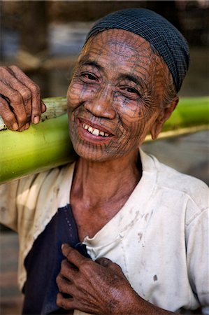 Myanmar,Chin State,Panbaung. A Chin woman with tattooed face carries home the stem of a banana tree. It was customary in the past for girls to be tattooed at 14 or 15 years old. Stock Photo - Rights-Managed, Code: 862-03365317