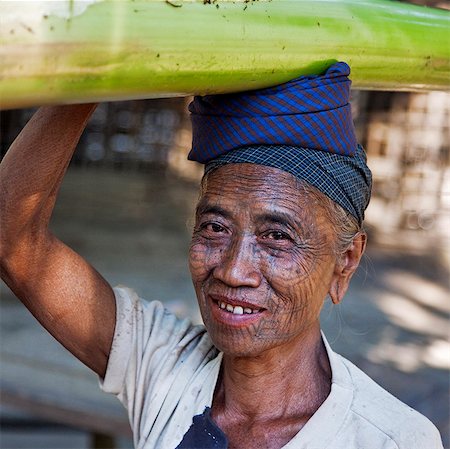 Myanmar,Chin State,Panbaung. A Chin woman with tattooed face carries home the stem of a banana tree. It was customary in the past for girls to be tattooed at 14 or 15 years old. Stock Photo - Rights-Managed, Code: 862-03365318