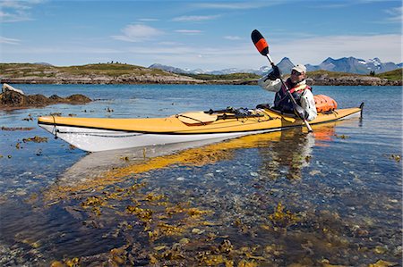 sports and kayaking - Norway,Nordland,Helgeland. Sea kayaking in coastal Norway during the summer,a guide demonstrated varoius kayaking strokes and techniques in a brightly coloured canoe. Stock Photo - Rights-Managed, Code: 862-03365670