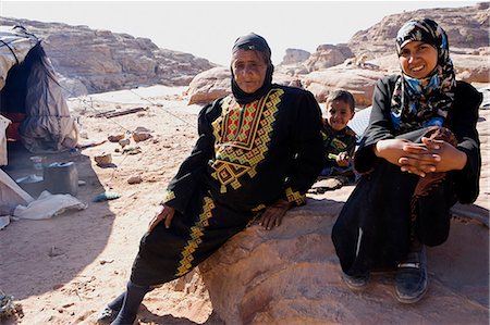 petra - Jordan,Petra Region. Wearing traditional Jordanian dress,former residents rest near their encampment outside of the archeological site. Foto de stock - Con derechos protegidos, Código: 862-03365900