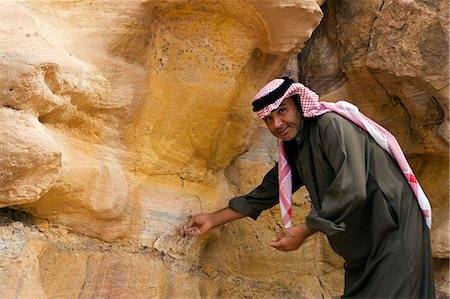 Jordanie, Petra, El Mraibet. Un guide bédouin local fait remarquer certains de la géologie complexe des gisements de grès près de la capitale Nabeatean de Pétra. Photographie de stock - Rights-Managed, Code: 862-03365926