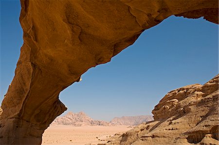 Jordan,Aqaba Region,Wadi Rum. Wadi Rum is one of the world's most spectacular desert landscapes- here a 'Burda',a natural rock bridge,overlooks the surrounding desert. Stock Photo - Rights-Managed, Code: 862-03365940