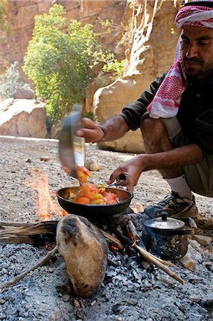 Jordan, Petra, Wadi Daphna. Ein lokalen Beduinen-Führer in traditioneller Kleidung gekleidet bereitet ein Mittagessen Zeit Essen über offenem Feuer in die Toten Kluft im Wadi Daphna. Stockbilder - Lizenzpflichtiges, Bildnummer: 862-03365942