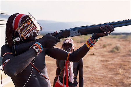 samburu - Samburu moran (warrior) tries the feel of a shotgun at the end of a bird shooting safari. Foto de stock - Con derechos protegidos, Código: 862-03365956