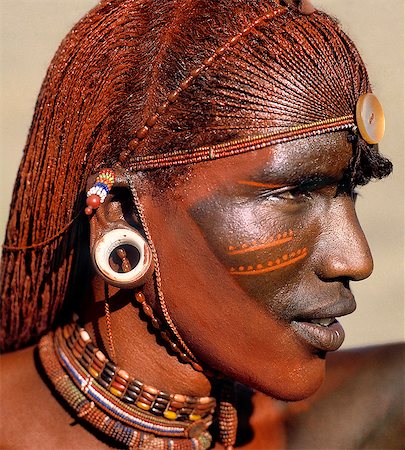 A Samburu warrior resplendent with long,braided,Ochred hair. The round ear ornaments of the warriors are fashioned from ivory. Samburu warriors are vain and proud,taking great trouble over their appearance. Ochre is a natural earth containing ferric oxide which is mixed with animal fat to the consistency of greasepaint. Foto de stock - Con derechos protegidos, Código: 862-03366036