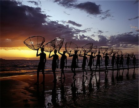 fishermen in africa - As the sun rises over Lake Turkana,a group of fishermen set out with their traditional fishing baskets to catch talapia in the lake's shallow waters. These traditional methods of fishing are now rare because the introduction of small mesh gillnets has resulted in a marked decline of fish stocks close to the shore. Stock Photo - Rights-Managed, Code: 862-03366077