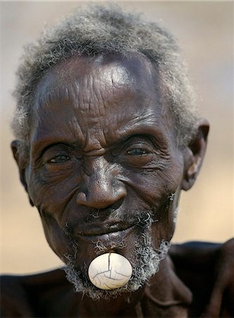 simsearch:862-03888776,k - Turkana elders wear decorative ivory lip ornaments,secured in position by a spigot which is inserted in a hole pierced below the man's lower lip after initiation. This singular form of decoration was once widespread but is rarely seen today. Stock Photo - Rights-Managed, Code: 862-03366101