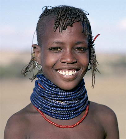 A pretty young Turkana girl has already had the flesh below her lower lip pierced in readiness for a brass ornament after her marriage. The rims of her ears have also been pierced and the holes kept open with small wooden sticks. Foto de stock - Con derechos protegidos, Código: 862-03366114