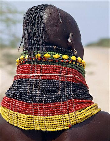 A Turkana girl's necklaces are well-oiled with animal fat and glisten in the sun. Occasionally,a girl will put on so many necklaces that her vertebrae stretch and her neck muscles gradually weaken. The partially shaven head is typical of Turkana women and girls. Stock Photo - Rights-Managed, Code: 862-03366111