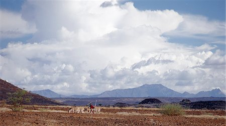 simsearch:862-03820278,k - A Turkana man drives his donkeys through lava fields as clouds gather above Mount Nyiru. Stock Photo - Rights-Managed, Code: 862-03366131