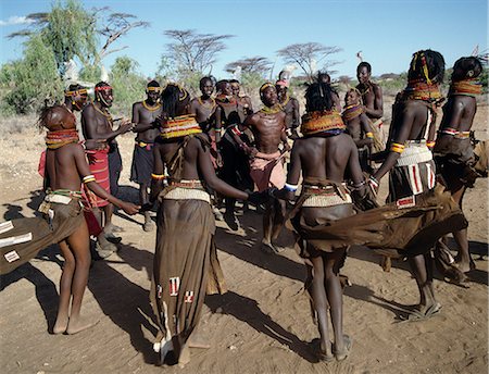 simsearch:862-03820349,k - Song is an art form ingrained in Turkana culture. At the end of a dance session,the participants invariably enjoy the Song of the Bulls. Each young man will take centre-stage to extol the praises of his favourite ox. He will explain how it came into his possession,its distinguishing traits and with outstretched arms,imitate the shape of its horns. Foto de stock - Direito Controlado, Número: 862-03366132