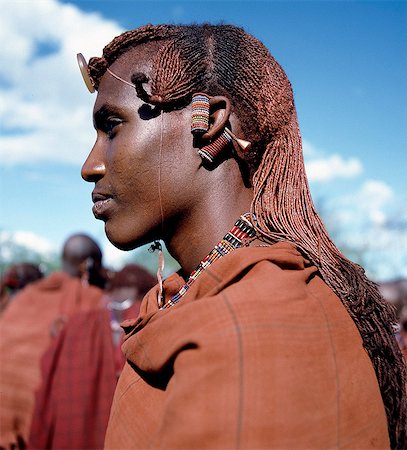 simsearch:862-03355144,k - Kenya,Kajiado,Maparasha. A Maasai warrior resplendent with long,ochred braids. This singular form of hairstyle distinguishes warriors from the rest of their society. This man has looped his elongated and decorated earlobes over his ears - a common practice when walking through thorn scrub country to prevent the loops being snagged by thorns. Stock Photo - Rights-Managed, Code: 862-03366149