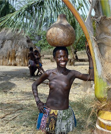 simsearch:862-03820415,k - A Giriama girl from Kenya's Coast Province carrying a gourd full of water on her head. Her small skirt is made from strips of printed cotton material. Foto de stock - Con derechos protegidos, Código: 862-03366188